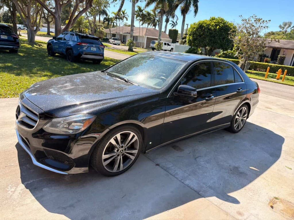 Black Mercedes-Benz E-Class sedan with dusty paint on a driveway before detailing