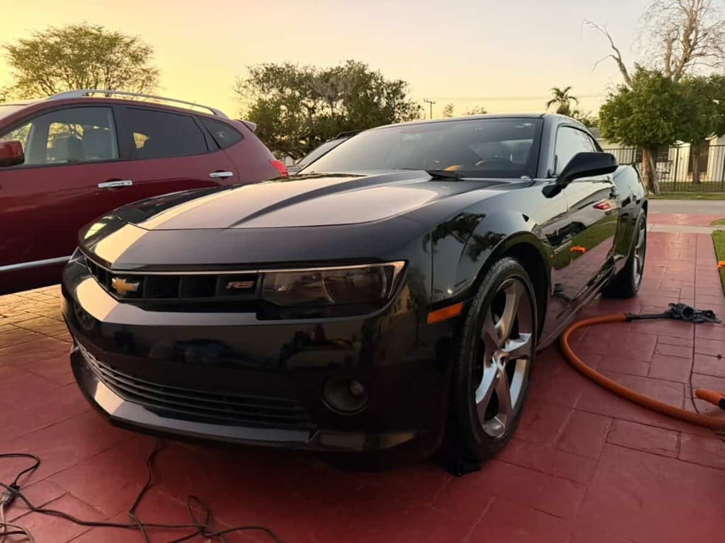 Black Chevrolet Camaro RS at golden hour on red tile driveway